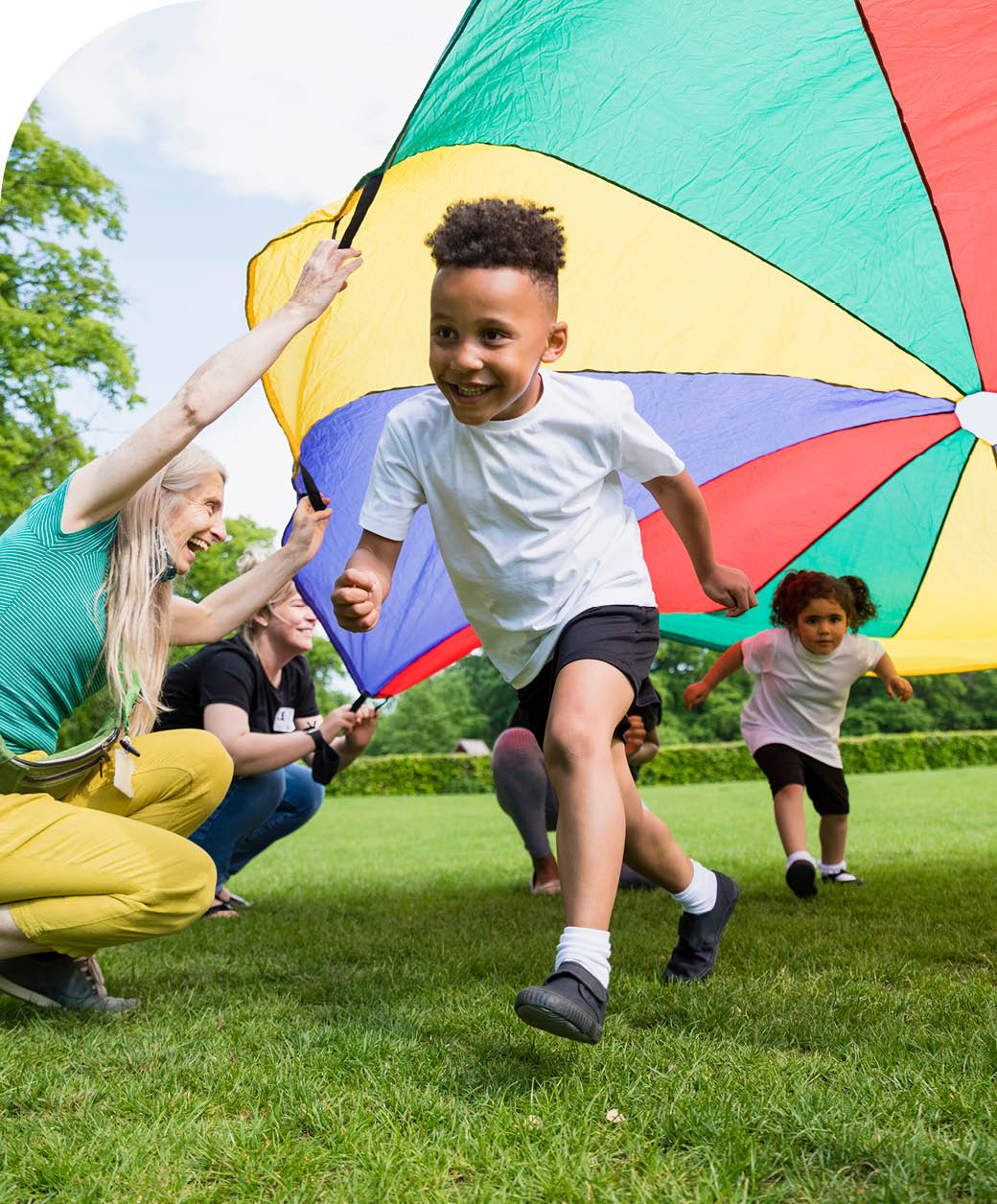 Children playing with a parachute at school during pe in the North East of England. A boy is running underneath it.